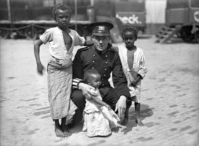 832162 Afbeelding van een verkeersagent met drie Somalische kinderen, vermoedelijk behorende bij het Circus Carl ...